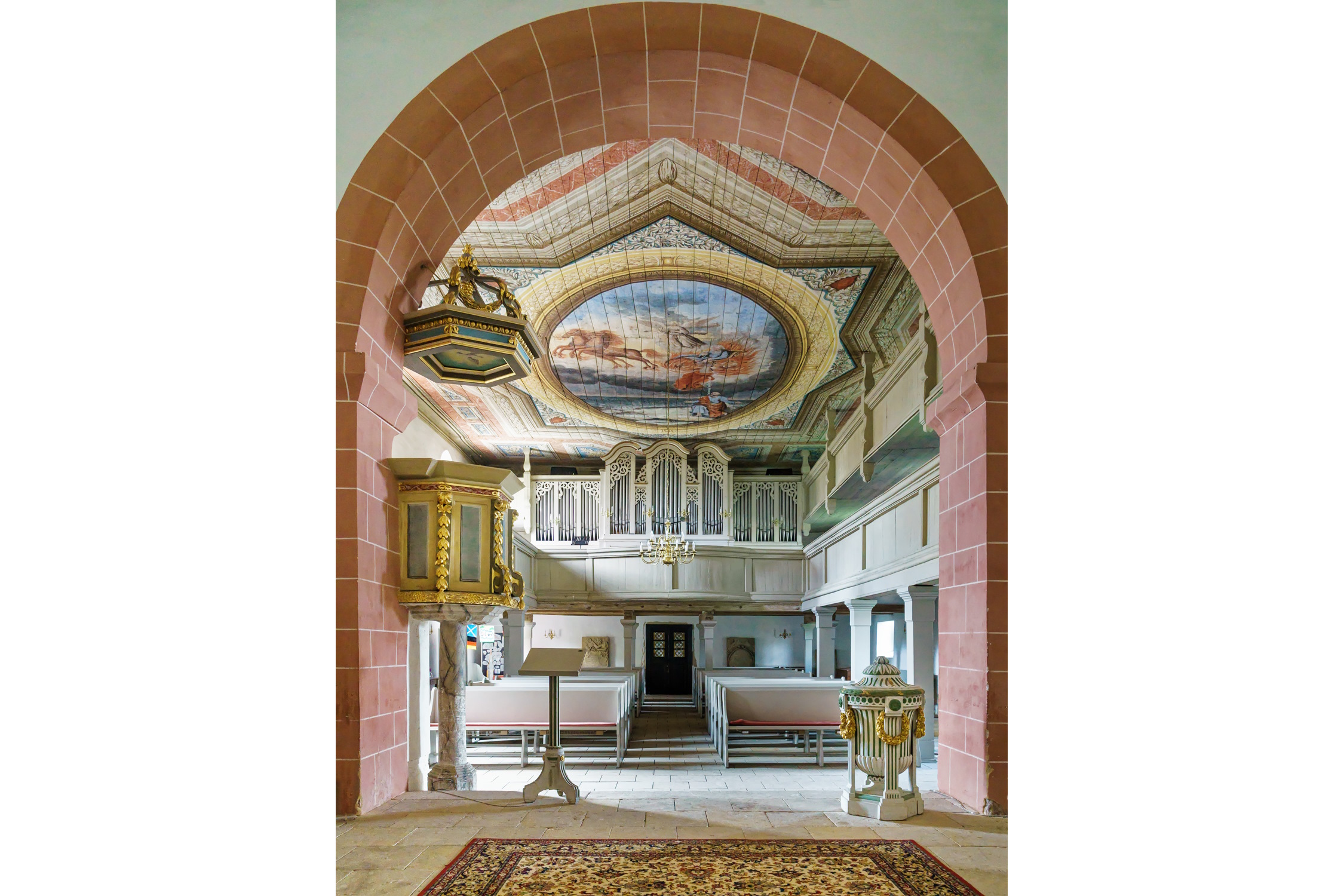 Ein Blick vom Altar zu Kanzel, Deckengemälde, Empore mit Orgel sowie Taufbecken. Foto: Radler59, CC BY-SA 4.0, https://commons.wikimedia.org/w/index.php?curid=137880774 